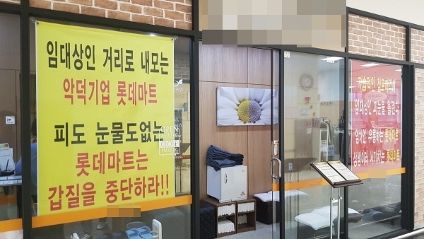 롯데마트 수지점의 한 점주가 가게에 플래카드를 내걸고 롯데마트의 횡포를 주장하고 있다.