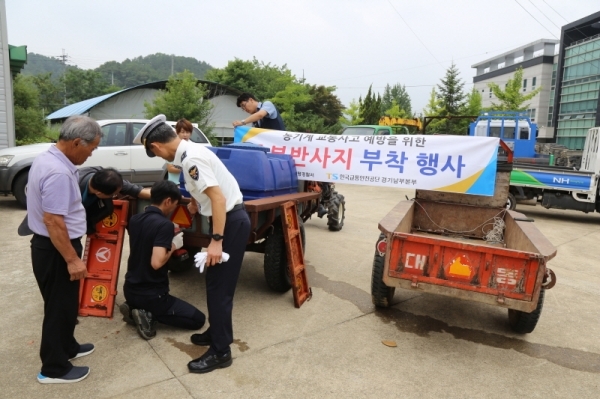 양평경찰서 경찰관들이 사고방지를 위해 경운기 뒷면에 반사판을  부착하고있다.