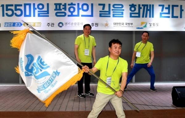 5일 파주시 임진각 DMZ생태관광지원센터에서 “DMZ 155마일 평화의 길을 함께 걷다”란 주제로 열린 ‘DMZ 155마일 대장정 출정식’에서  유동규 경기관광공사 사장으로 부터 단기를 전달받은 걷기대원 대표가 단기를 흔들고 있다.전형민기자