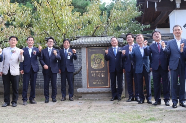 정동균 양평군수와 이정우 의장을 비롯한 참석자들이 세미원이 경기도지정정원1호라고 기록된 표지판을 제막하고 기념 촬영을 하고 있다.