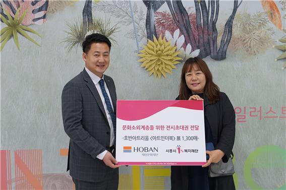 호반아트리움 송진오 차장이 전시초대권 1천300매를 시흥시1%복지재단 천숙향 사무국장에게 전달하고 있다.