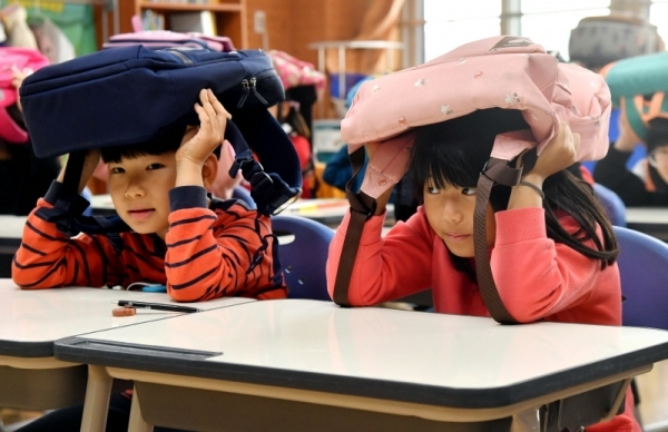 29일 수원시 팔달구 연무초등학교에서 ‘2019 재난대응 안전한국훈련’의 일환으로 열린 지진발생에 따른 건축물 붕괴 및 화재 상황을 가상한 훈련에서 학생들이 가방으로 머리를 보호하고 있다. 전형민기자