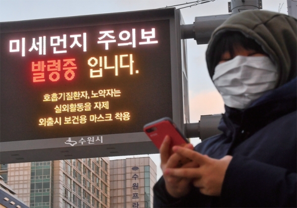수도권지역에 미세먼지주의보 및 한파주의보가 내려진 18일 오후 수원시청 인근 대기환경 전광판 앞에서 한 시민이 방한복과 마스크를 착용한 채 버스를 기다리고 있다. 한편 기상청은 “19일 경기ㆍ인천지역에 한파가 찾아올 것으로 예보, 건강 관리에 유의해줄 것”을 당부했다. 윤원규기자