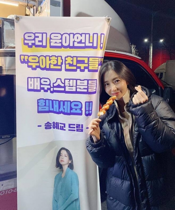 배우 송윤아가 송혜교에게 선물 받은 간식차 옆에서 포즈를 취하고 있다. 인스타그램