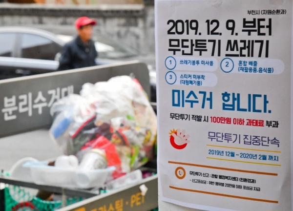 9일 오후 부천시 한 주택가에 무단투기 쓰레기 미수거를 알리는 안내문 너머로 일반 비닐봉투에 담겨 버려진 쓰레기가 쌓여있다. 수도권매립지는 종량제 봉투 미사용, 재활용품과 음식물쓰레기를 일반쓰레기와 섞는 등 무단투기 생활폐기물이 전체 폐기물의 15%를 초과하면 반입을 규제하는데 부천시는 지난 10월,11월에 15%를 초과해 9일부터 무단투기 쓰레기 미수거란 대책을 내놓았다. 윤원규 기자