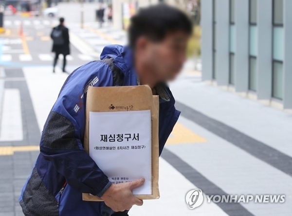 화성연쇄살인 8차 사건의 범인으로 검거돼 20년간 '억울한 옥살이'를 했다고 주장해 온 윤모씨가 재심청구서를 들고 지난 11월 13일 수원지방법원으로 들어가고 있는 모습. 연합뉴스