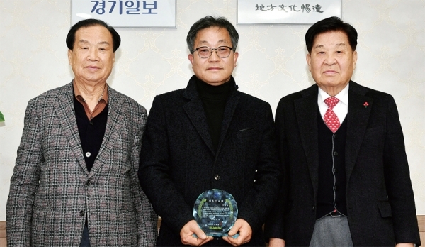 정년퇴임을 맞은 경기일보 이성남 기자(가운데)가 본보 신선철 회장‚ 신항철 대표이사 사장 등에게 재직기념패를 받고 있다. 김시범기자