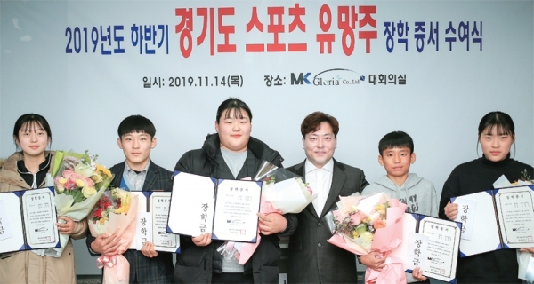 지난해 11월 14일 MK글로리아 회의실에서 열린 2019 하반기 경기도 스포츠 유망주 장학증서 수여식에서 장민기 MK홀딩스 회장(오른쪽 3번째)이 스포츠 꿈나무들에게 장학금을 전달한 뒤 기념촬영을 하고 있다. 왼쪽부터 펜싱 이수빈, 레슬링 김주영, 역도 박혜정, 장민기 회장, 육상 김도연 양, 궁 박예진. 사진=MK글로리아 제공