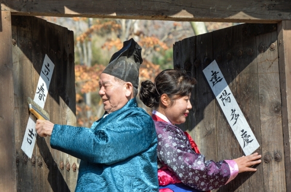 입춘을 하루 앞둔 3일 용인시 기흥구 한국민속촌에서 어르신들이 양반가 대문에 입춘대길 건양다경 (立春大吉 建陽多慶)이 적힌 입춘방(立春榜)을 붙이고 있다.조주현기자