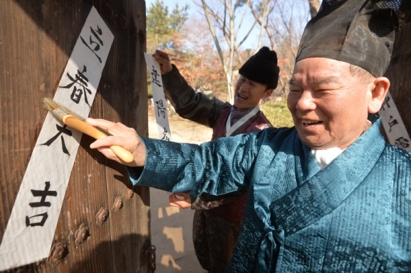 입춘을 하루 앞둔 3일 용인시 기흥구 한국민속촌에서 어르신들이 양반가 대문에 입춘대길 건양다경 (立春大吉 建陽多慶)이 적힌 입춘방(立春榜)을 붙이고 있다.조주현기자