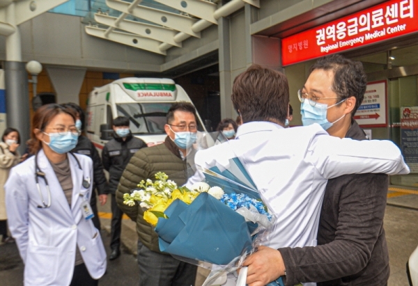 코로나 19 국내 확진환자 중 3명이 완치판정을 받은 12일 오후 고양시 명지병원에서 17번 확진자가 퇴원을 하며 의료진과 포옹하고 있다. 조주현기자