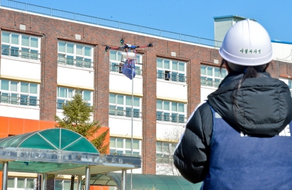 18일 오전 수원 영화초등학교에서 사회적 기업 '사람과 자연 협동조합' 및 수원농생명과학고 내 '더 드론' 동아리 학생들이 방재용 드론을 이용해 수원시 관내 초,중,고교의 코로나19 확산 방지를 위한 방역 활동을 펼치고 있다. 윤원규기자