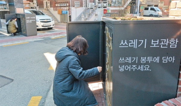 18일 오후 수원시 영통구 매탄4동 일원의 주택가에서 주민들이 환경미화를 위해 자체적으로 설치한 쓰레기 보관함을 확인하고 있다. 윤원규기자