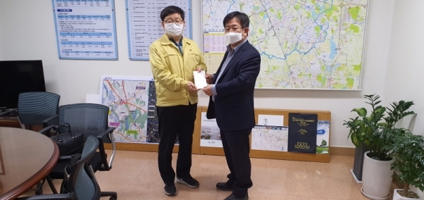이정섭 팔달구 마을만들기협의회장(오른쪽)이 김용덕 수원시 안전교통국장에게 코로나19 관련 성금을 전달하고 있다. 수원시 제공