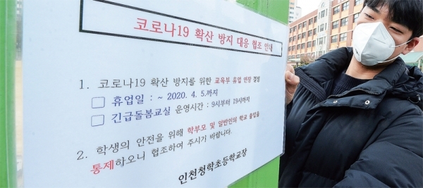 17일 인천시 연수구 청학초등학교 관계자가 신학기 개학 3차 연기에 따라 휴업 연장 안내문을 교문에 붙이고 있다. 장용준기자