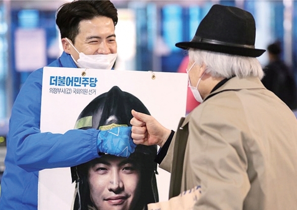 더불어민주당 오영환 후보가 시민들과 주먹 인사를 나누고 있다.
