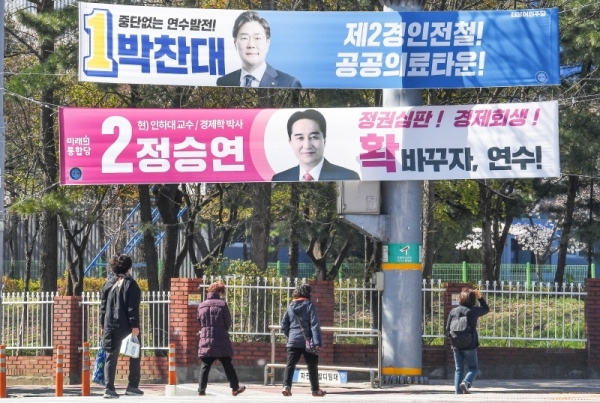 제21대 국회의원 선거(총선) 여론조사 결과 공표 금지일을 하루 앞둔 8일  인천시 연수구 먼우금사거리 유권자들이 연수 갑에 출마한 후보 현수막 앞을 지나고 있다. 장용준기자