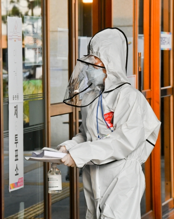 제21대 국회의원선거가 열린 15일 오후 수원시청 야외 코로나19 임시 기표소에서 수원시 자가격리자가 투표한 용지를 방호복을 입은 관계자가 정리하고 있다. 윤원규기자