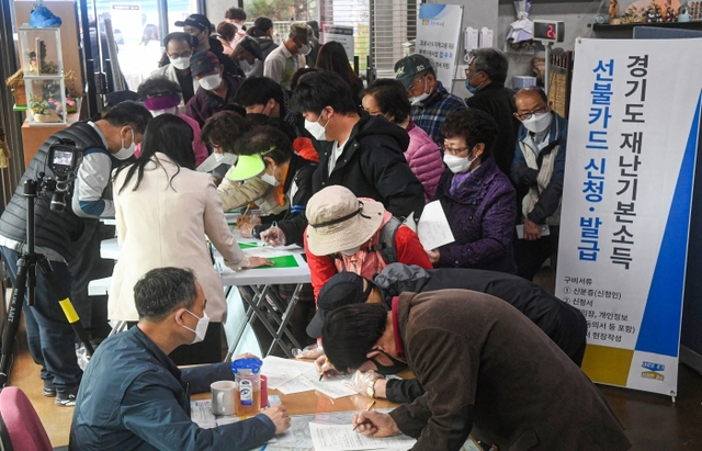 경기도재난기본소득 현장신청이 시작된 20일 오전 송죽동행정복지센터 접수처에서 시민이 재난기본소득 현장신청을 하고 있다. 조주현기자