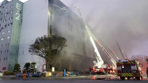 21일 발생한 군포시 부곡동 군포복합물류센터 화재가 일몰 후 강풍으로 꼭대기층으로 번지자 소방관들이 고가사다리차와 굴절차를 이용해 진화작업을 벌이고 있다.