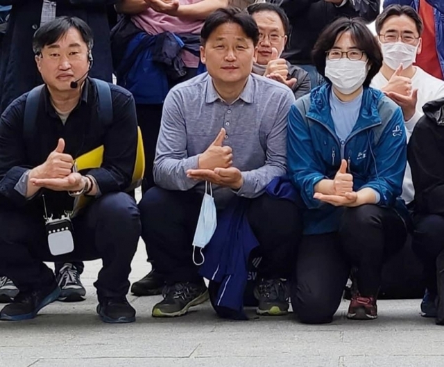 ▲ (왼쪽부터)김준혁 한신대 교수와 더불어민주당 김영진 의원(수원병), 김 의원의 부인이 엄지를 치켜세운 오른손을 왼손으로 받치는 동작을 취하며 '덕분에 챌린지'에 참여하고 있다. 사진=김영진 의원 페이스북 제공