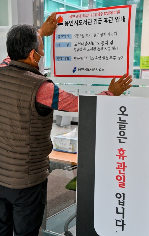 9일 오후 용인 수지도서관에서 직원이 긴급휴관 안내문을 붙이고 있다. 용인시는 이태원 클럽을 다녀온 20대가 코로나19 확진 판정을 받으면서 부분 개장했던 공공도서관 17개와 공공 수영장 6개를 11일까지 긴급 휴관한다. 윤원규기자