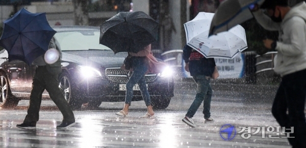 인천을 비롯한 수도권지역에 천둥과 돌풍을 동반한 비가 내린 18일 오후 우산을 받처 든 시민이 밤같이 어두워진 인천버스종합터미널 사거리 횡단보도에서 발걸음을 재촉하고 있다. 장용준기자