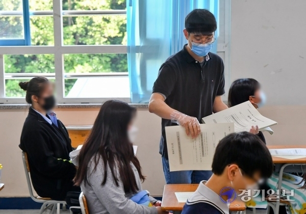 고등학교 3학년생을 대상으로 한 5월 전국연합학력평가가 실시된 21일 오전 수원시 장안구 조원고등학교에서 교사가 비닐장갑을 끼고 시험지를 나눠주고 있다. 윤원규기자