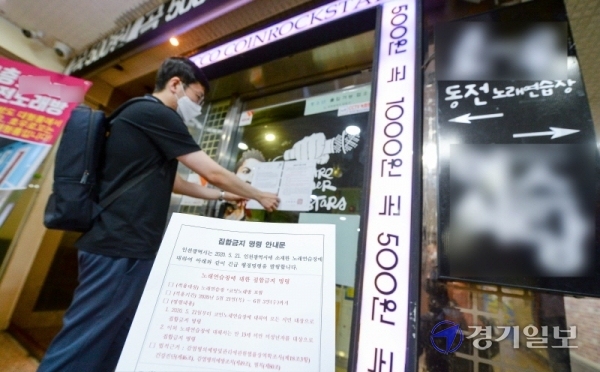 코로나19 확진 판정을 받은 인천 학원강사를 고리로 지역 감염이 확산하자, 인천시가 관내 코인노래방에 2주간 집합금지 명령을 내린 21일 남동구청 관계자가 구월동 로데오거리의 한 코인 노래방 출입문에 집합금지 명령 안내문을 붙이고 있다. 장용준기자