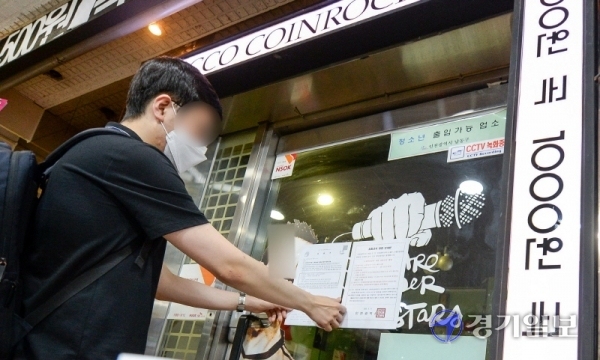 코로나19 확진 판정을 받은 인천 학원강사를 고리로 지역 감염이 확산하자, 인천시가 관내 코인노래방에 2주간 집합금지 명령을 내린 21일 남동구청 관계자가 구월동 로데오거리의 한 코인 노래방 출입문에 집합금지 명령 안내문을 붙이고 있다. 장용준기자
