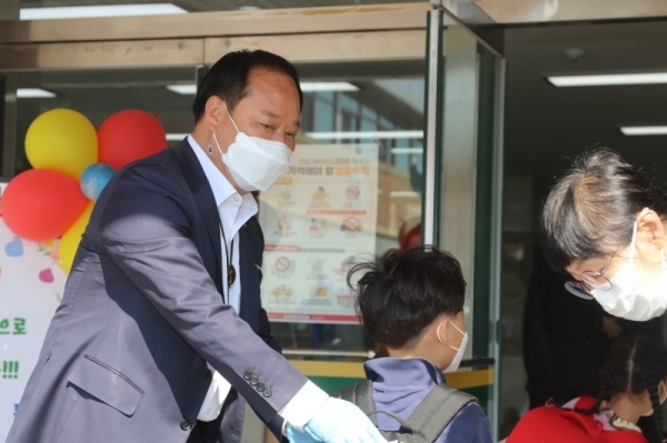 붙이는체온계를 목에 붙인 정동균 양평군수가 27일 오전 양평동초등하교에서 첫 등교를 하는 학생들을 맞이하고 있다.