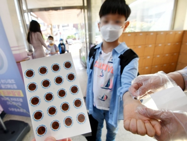29일 오전 수원 영화초등학교에서 교사들이 등교하는 학생들에게 '붙이는 체온계'를 붙여주고 있다. 코로나19 예방을 위해 개발된 '붙이는 체온계'는 체온이 37.5도 이상일때 색상이 변하는 스티커로 교사나 학부모가 학생들의 발열상황을 즉시 알 수 있어 인기가 높아지고 있다. 김시범기자