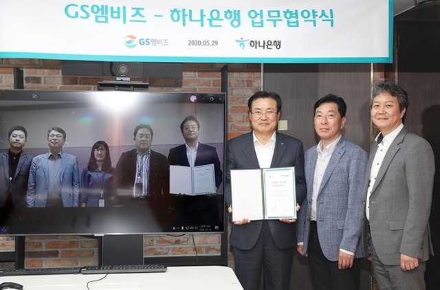 ▲하나은행은 지난 29일 오후 자동차 종합 서비스 기업 GS엠비즈㈜와 자동차 생활 금융서비스를 위한 전략적 업무 협약을 체결했다. 정석화 하나은행 리테일그룹장(사진 오른쪽에서 세번째)이 서울 중구 을지로 소재 하나은행 본점에서 김철민 GS엠비즈 전무(사진 오른쪽에서 네번째)와 화상 영상을 통해 업무 협약 체결 후, 기념사진 촬영을 하고 있다.<br>