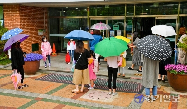 2일 오후 수원시 권선구의 한 초등학교에서 학부모들이 우산을 들고 아이들과 하교하고 있다. 경기도 곳곳에서 코로나19가 발생하는 가운데 3일부터 고1·중2·초3∼4학년들의 등교 수업이 예정돼있어 학부모들의 불안감도 커져가고 있다. 윤원규기자