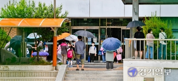 2일 오후 수원시 권선구의 한 초등학교에서 학부모들이 우산을 들고 아이들과 하교하고 있다. 경기도 곳곳에서 코로나19가 발생하는 가운데 3일부터 고1·중2·초3∼4학년들의 등교 수업이 예정돼있어 학부모들의 불안감도 커져가고 있다. 윤원규기자