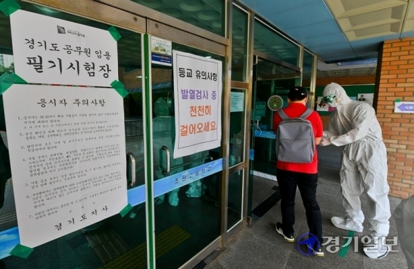 '2020년도 경기도 8·9급 지방직 공무원 공채 필기시험'이 열린 13일 오전 수원시의 한 시험장에서 수험생들이 입장 전 체온 측정과 손 소독을 하고 있다. 올해 경기도 8·9급 전체 4,978명 선발 예정에 4만2261명이 응시하면서 8.5의 경쟁률을 보였다. 윤원규기자