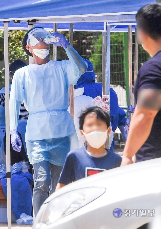 14일 코로나19 확진자가 발생한 인천시 계양구 효성초등학교에 설치된 선별진료소에서  불볕더위에 지친 한 의료진이 연신 생수를 들이키고 있다. 장용준기자