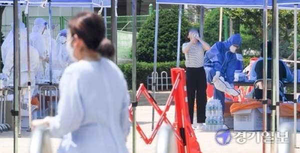 14일 코로나19 확진자가 발생한 인천시 계양구 효성초등학교에 설치된 선별진료소에서  불볕더위에 지친 한 의료진이 연신 생수를 들이키고 있다. 장용준기자