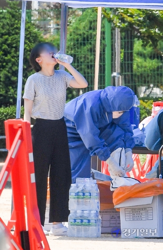 14일 코로나19 확진자가 발생한 인천시 계양구 효성초등학교에 설치된 선별진료소에서  불볕더위에 지친 한 의료진이 연신 생수를 들이키고 있다. 장용준기자