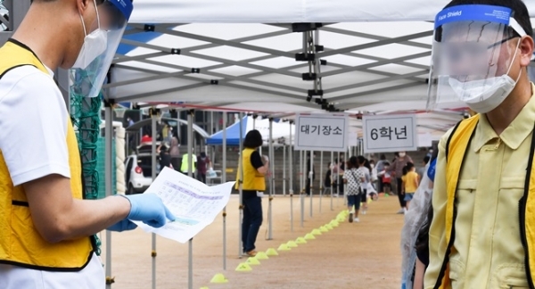17일 오전 코로나19 확진자가 나온 인천시 미추홀구의 한 초등학교 정문에서 학교 관계자가 검체 검사를 받을 학생 인원을 확인하고 있다. 장용준기자