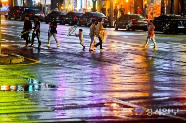 장맛비가 내린 24일 오후 비에 젖은 수원의 한 도로 위로 상가들의 조명이 반사돼 화려한 야경을 연출하고 있다. 윤원규기자