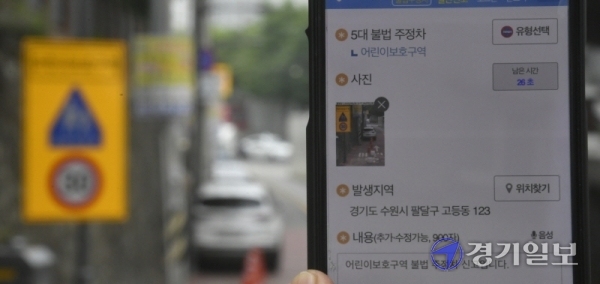 어린이보호구역 내 불법 주정차 주민신고제가 시행된 29일 오후 수원시 팔달구 수원초등학교 주변 도로에서 한 시민이 국민신문고 앱을 통해 불법 주차 차량을 신고하고 있다.조주현기자