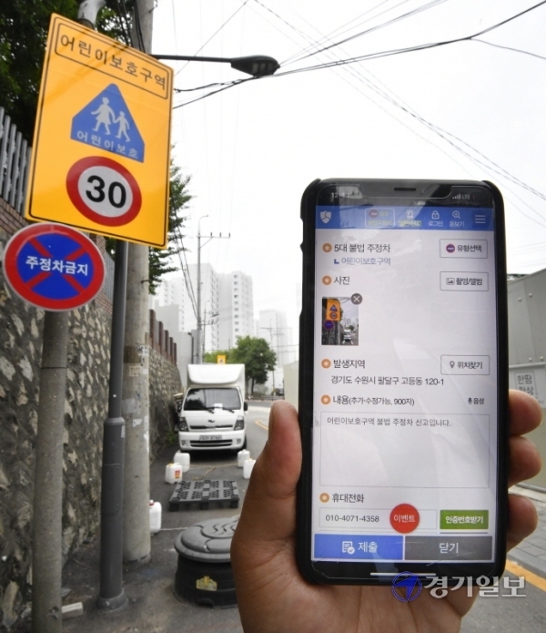 어린이보호구역 내 불법 주정차 주민신고제가 시행된 29일 오후 수원시 팔달구 수원초등학교 주변 도로에서 한 시민이 국민신문고 앱을 통해 불법 주차 차량을 신고하고 있다.조주현기자