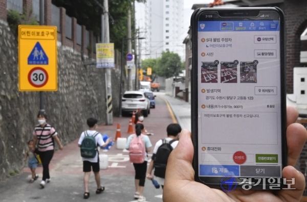 어린이보호구역 내 불법 주정차 주민신고제가 시행된 29일 오후 수원시 팔달구 수원초등학교 주변 도로에서 한 시민이 국민신문고 앱을 통해 불법 주차 차량을 신고하고 있다.조주현기자