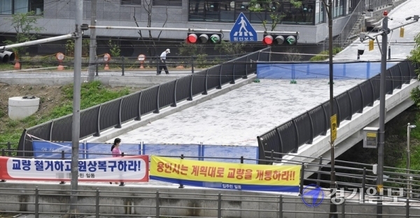 2일 오후 용인시 수지구 소재 두개의 아파트단지 사이를 흐르는 성복천에 설치된 교량에 양측 아파트 입주민들이 각각 내건 현수막이 나란히 붙어있다. A아파트는 철거를, B아파트는 정상개통을 요구하면서 해당 교량은 개통되지 못한 채 방치되고 있다. 조주현기자