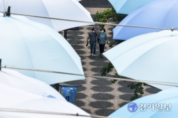 낮 기온이 30도 안팎의 불볕더위가 이어진 8일 인천시 연수구 송도동의 한 복합쇼핑몰을 찾은 시민이 시원스레 펼쳐진 우산거리를 지나고 있다. 장용준기자