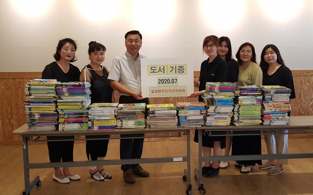 ▲길상면주민자치위가 센터에 기증한 도서를 놓고 기념촬영을 하고 있다.