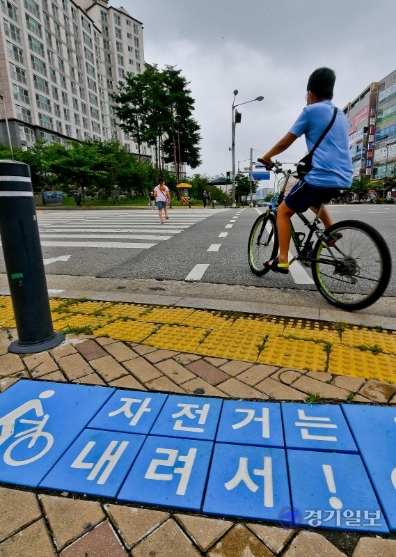 27일 수원시 권선구 금곡로 102번길 ‘자전거 횡단도’ 앞에 ‘자전거는 내려서’라는 사인블록이 붙어 있어 자전거 이용자들에게 혼란을 주고 있다. ‘자전거 횡단도’는  자전거에 탑승한 채 지나갈 수 있는 길이다. 윤원규기자