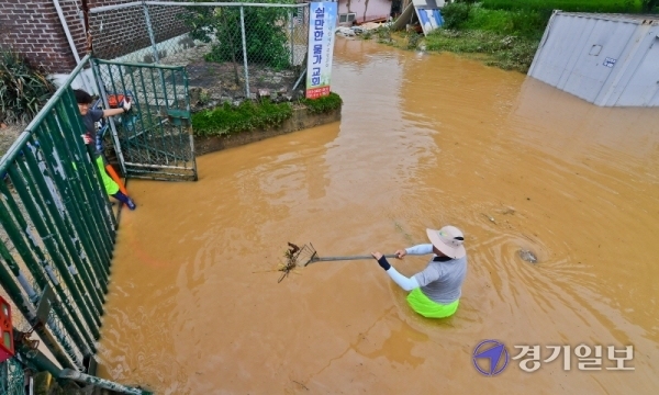 2일 오후 홍수 경보가 내려진 여주시 청미천의 원부교 일원 마을이 범람된 강물로 침수돼 관계자들이 양수기로 물을 빼내고 있다. 윤원규기자