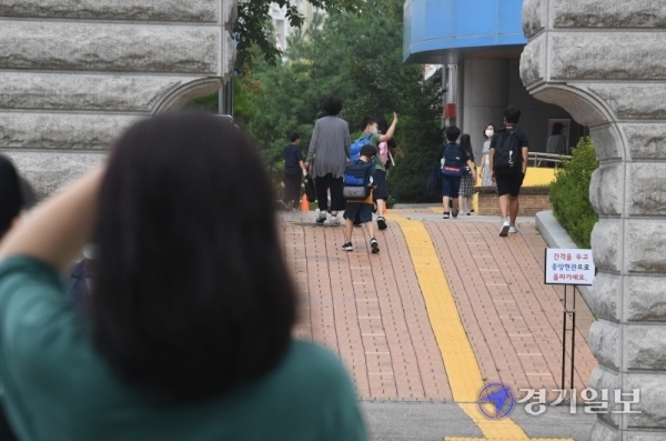 인천을 비롯한 수도권지역의 학교 밀집도 최소화 조치를 시작한 18일 오전 서구 초은 초등학교 교문에서 학부모들이 개학 등교에 나선 자녀들을 지켜보고 있다.이날 학교는 홀수학년에 홀수번호 학생들만 등교시켜 선제적인 1/4 밀집도 최소화 조치를 시행했다. 장용준기자